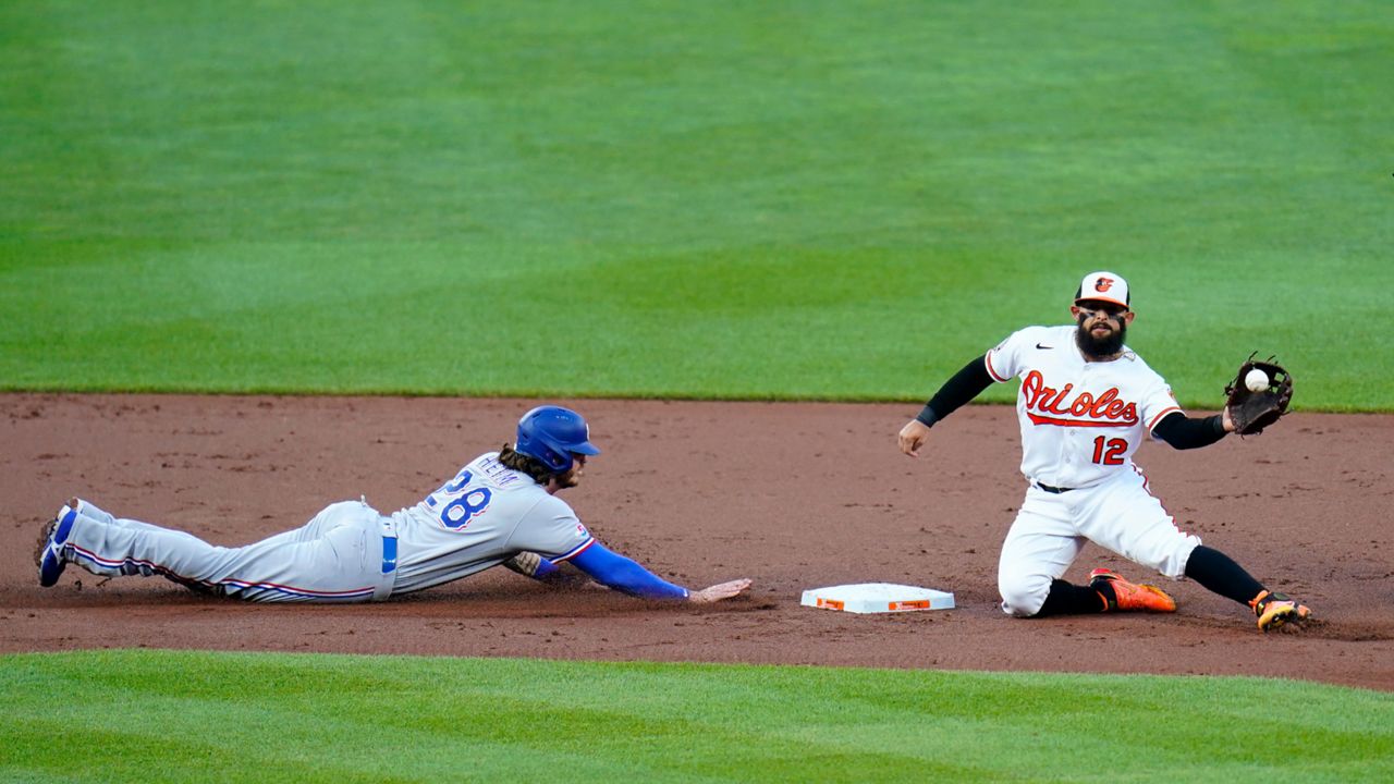 Baltimore Orioles second baseman Rougned Odor (12) catches a throw from catcher Robinson Chirinos, not visible, while trying to pick off Texas Rangers' Jonah Heim, left, at second base during the second inning of a baseball game, Tuesday, July 5, 2022, in Baltimore. (AP Photo/Julio Cortez)