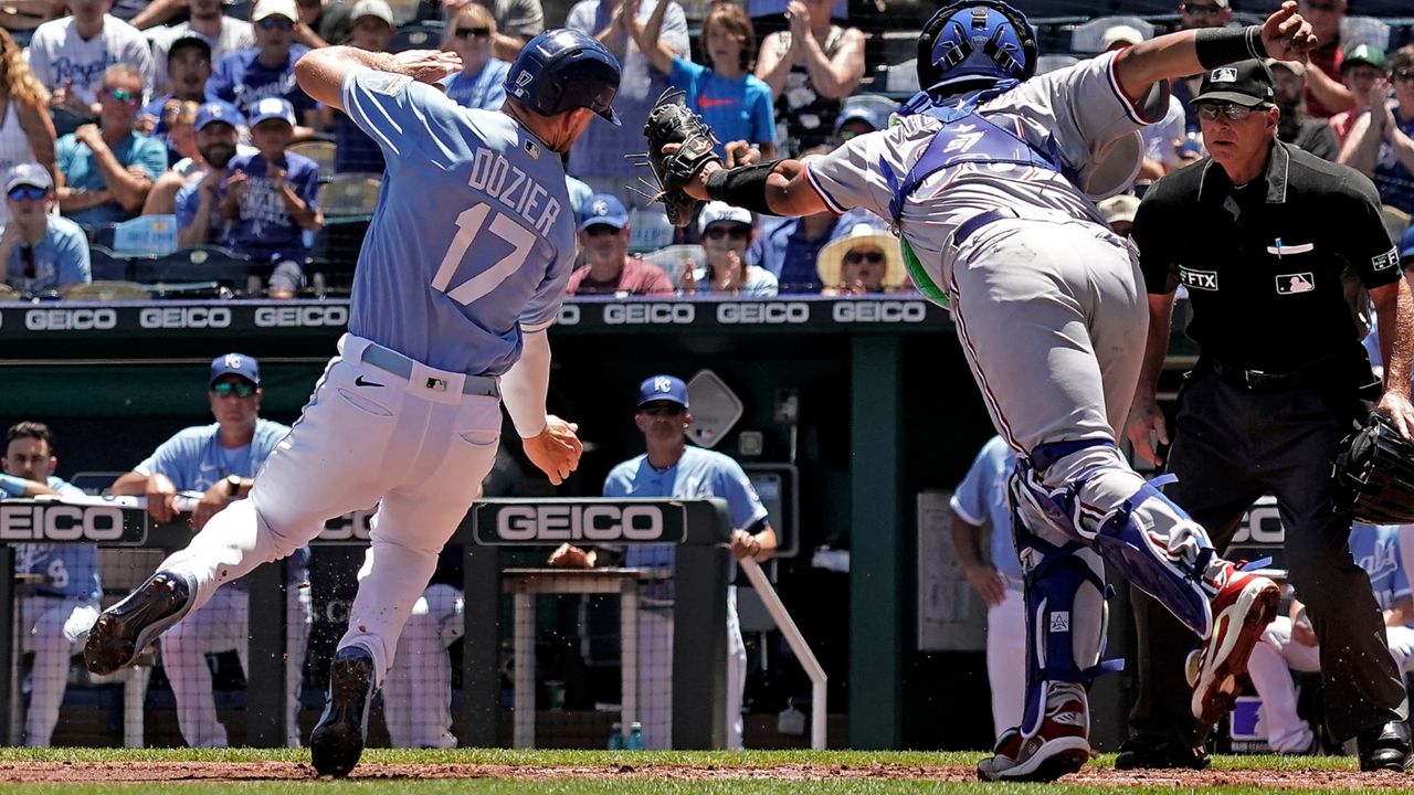 Kansas City Royals Hunter Dozier (17) is tagged out by Texas Rangers catcher Meibrys Viloria as he tried to score on a single by MJ Melendez during the first inning of a baseball game Wednesday, June 29, 2022, in Kansas City, Mo. (AP Photo/Charlie Riedel)