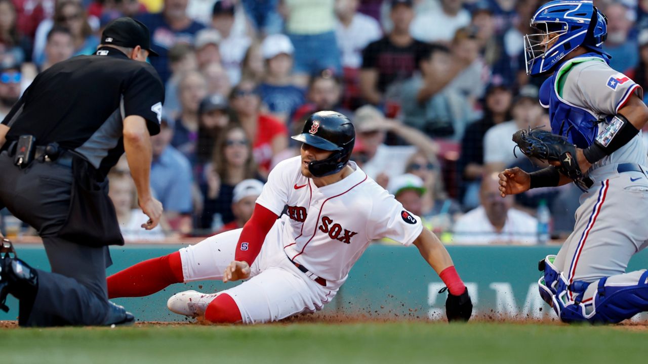Boston Red Sox's Enrique Hernandez, center, scores on a fielder's choice single by Xander Bogaerts after a missed catch error by Texas Rangers' Meibrys Viloria, right, during the fifth inning of a baseball game, Saturday, Sept. 3, 2022, in Boston. (AP Photo/Michael Dwyer)