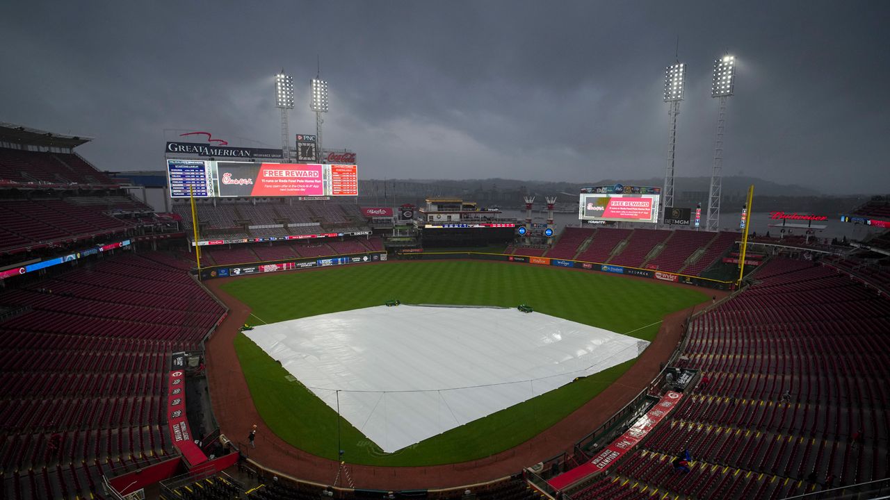 A view of the tarp on the field as rain falls before a baseball game against the Milwaukee Brewers and the Cincinnati Reds in Cincinnati, Wednesday, April 10, 2024. The game was delayed due to inclement weather. (AP Photo/Aaron Doster)