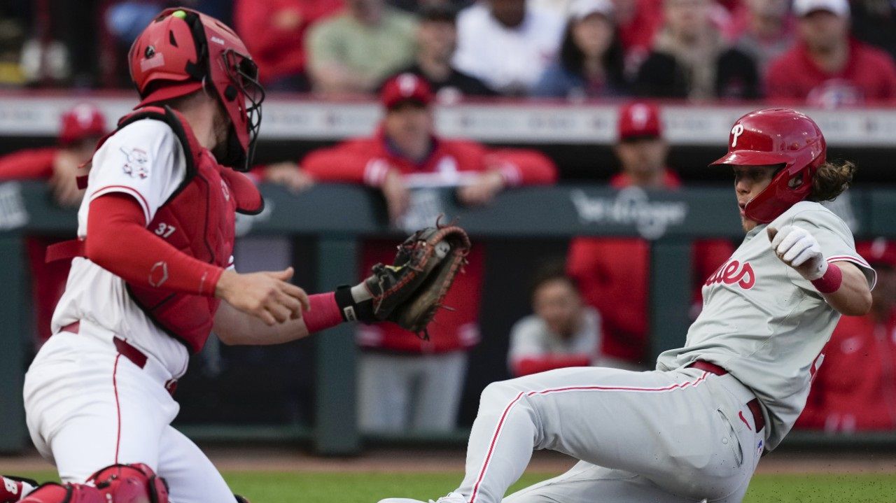 Philadelphia Phillies' Alec Bohm, right, safely slides into home to score on a sacrifice fly by teammate Bryson Scott as Cincinnati Reds catcher Tyler Stephenson, left, looks to tag in the second inning of a baseball game on Monday, April 22, 2024, in Cincinnati. (AP Photo/Carolyn Kaster)