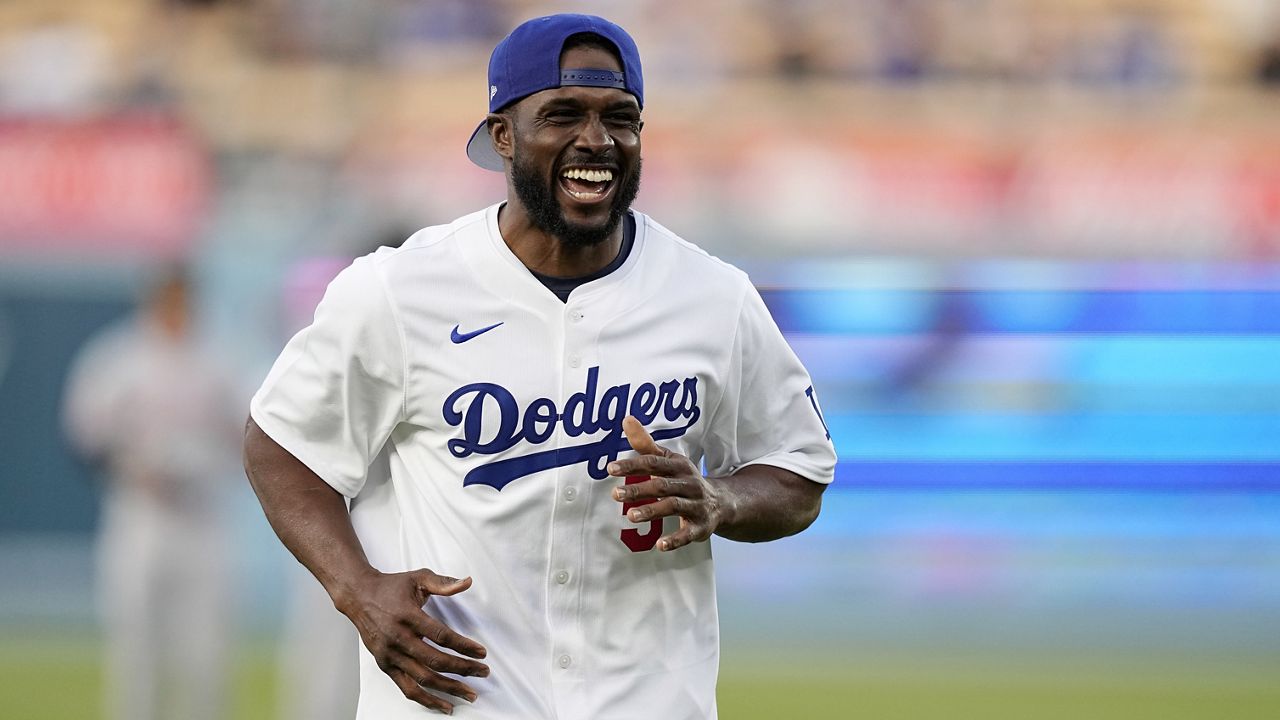 FILE - Former NFL and University of Southern California running back Reggie Bush, left, jokes with laughs after throwing out the ceremonial first pitch prior to a baseball game between the Los Angeles Dodgers and the Cincinnati Reds Friday, May 17, 2024, in Los Angeles. (AP Photo/Mark J. Terrill, File)