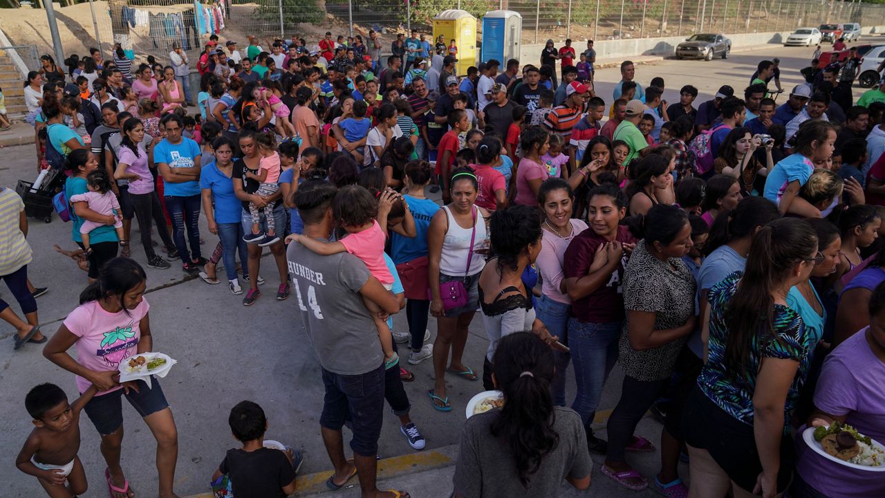 In this Aug. 30, 2019, file photo, migrants, most of who are asylum seekers that have been sent back to Mexico under the Migrant Protection Protocols to wait for their asylum cases, stand in line to get a meal at an encampment in Matamoros, Mexico. (AP Photo/Veronica G. Cardenas, File)