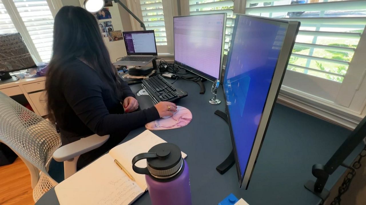 woman working remotely from home desk with monitors set up