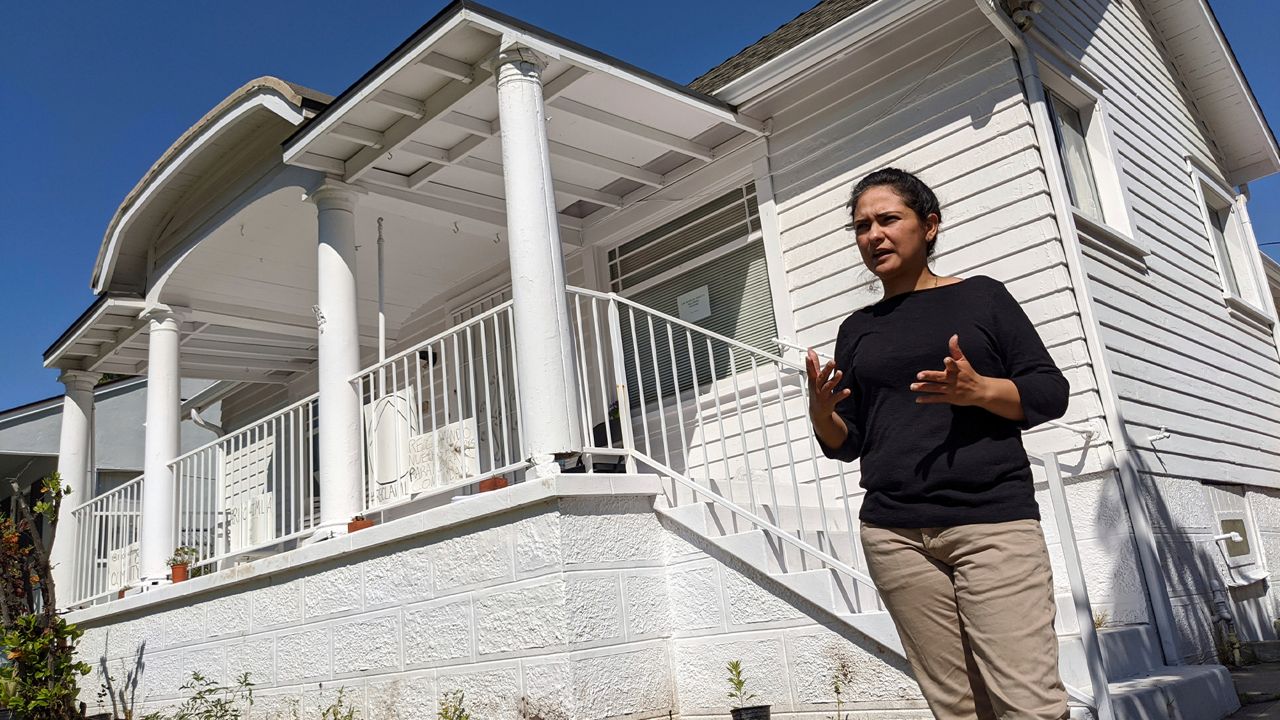 Homeless mother Ruby Gordillo pauses outside a formerly publicly owned vacant home, her family has moved in El Sereno neighborhood of Los Angeles on Monday, March 30, 2020. A group of homeless mothers have taken over vacant homes in Los Angeles as part of a growing movement to bring attention to the state's need for housing, especially during the coronavirus outbreak. They were inspired by women who made headlines for a similar action in 2019 in the San Francisco Bay Area. (AP Photo/Damian Dovarganes)