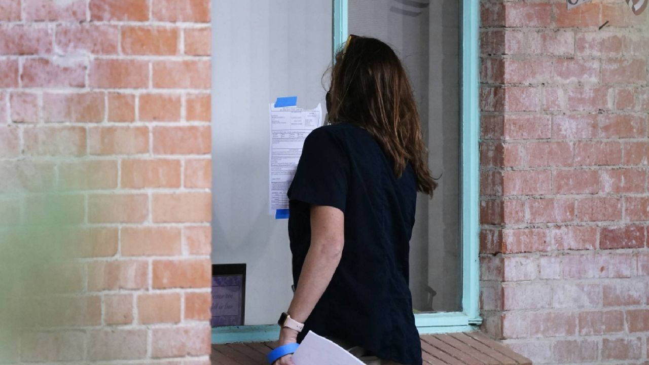 FILE - Pima County Constable Kristen Randall signs an eviction notice to a rental resident after taping the notice to the apartment window on Sept. 24, 2021, in Tucson, Ariz. (AP Photo/Ross D. Franklin, File)