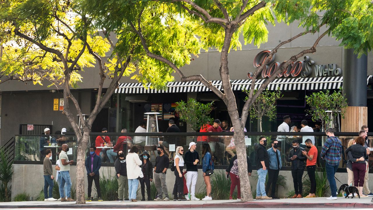 People wait in line for an open terrace table at a restaurant on Valentine's Day during the coronavirus pandemic, Sunday, Feb. 14, 2021, in West Hollywood, Calif. (AP Photo/Damian Dovarganes)