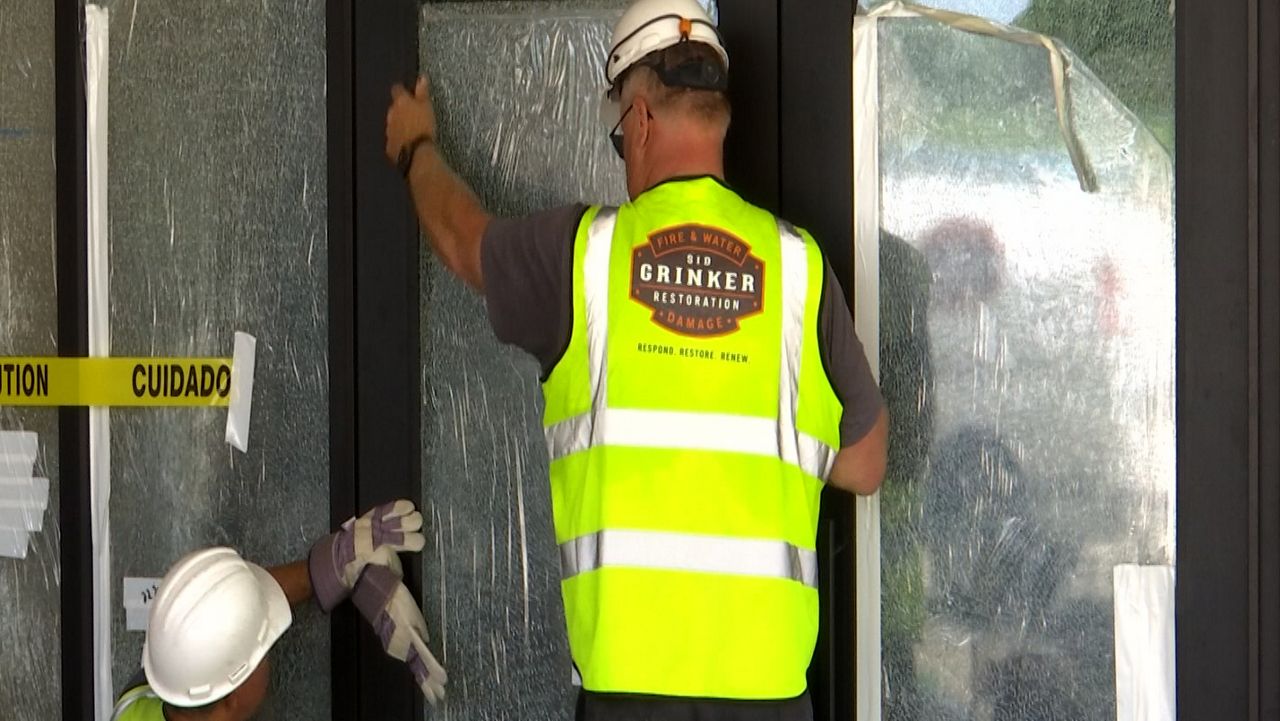 Restoration crews work Monday morning to replace glass that was broken by a vandal at Temple Menorah in Milwaukee. 