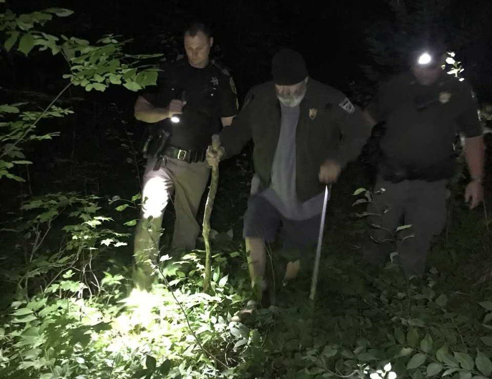 Game Warden Ryan Fitzpatrick and Aroostook County Sheriff Deputy Nate Chisom assist Donald Cook, 64, out of the woods in New Sweden early Friday morning. The Virginia man had gotten lost in the woods while looking for moose tracks. (Maine Department of Inland Fisheries & Wildlife)