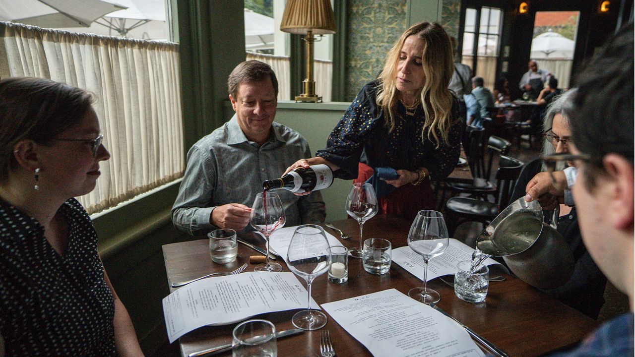 In this Saturday, June 19, 2021, photo, Caroline Styne, owner and wine director at The Lucques Group, serves wine to attorney Alec Nedelman, celebrating early "Father's Day "with his family at the A.O.C. Brentwood restaurant in Los Angeles.  (AP Photo/Damian Dovarganes)