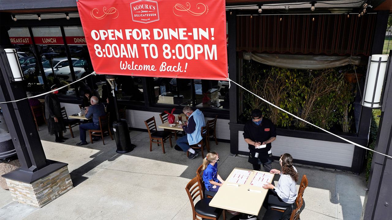 Diners Evie Costello, left, and Mandissa Costello, right, are served by Isaac Villaneva at Agoura's Famous Deli Sunday, March 14, 2021, in the Agoura Hills section of Los Angeles County.  (AP Photo/Mark J. Terrill)