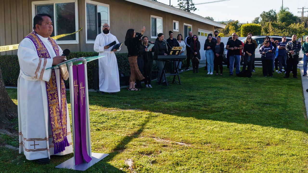 The Rev. Albert Avenido, left, and sacristan Hector Ibarra lead members of Sacred Heart Catholic Church in Covina, Calif., on a prayer vigil for Bishop David O'Connell near his home in Hacienda Heights, Calif., on Sunday. (AP Photo/Damian Dovarganes)