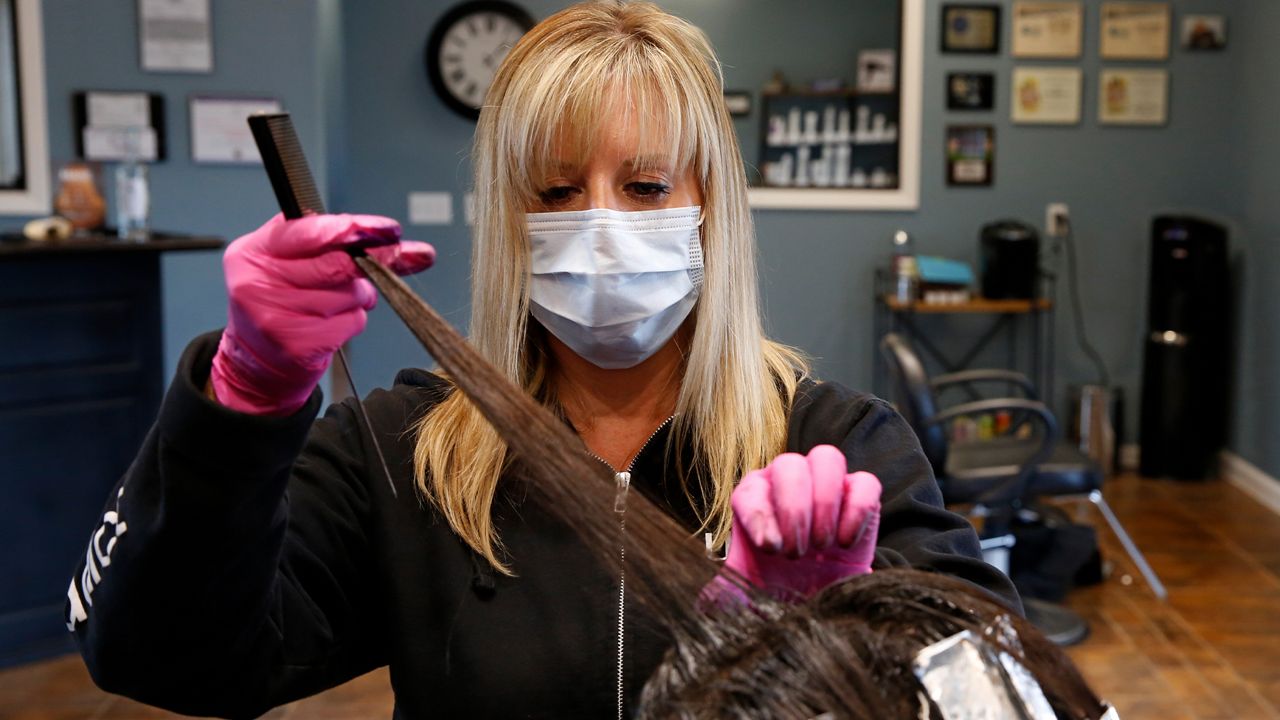 Tisha Fernhoff separates the hair of a client receiving a color refreshing at the Beauty Bar Salon in Auburn, Calif., Wednesday, April 29, 2020. Fernhoff, who closed her shop six weeks earlier because of the mandatory stay-at-home order amid the new coronavirus, recently began taking an occasional client in order pay her rent and meet other expenses. (AP Photo/Rich Pedroncelli)