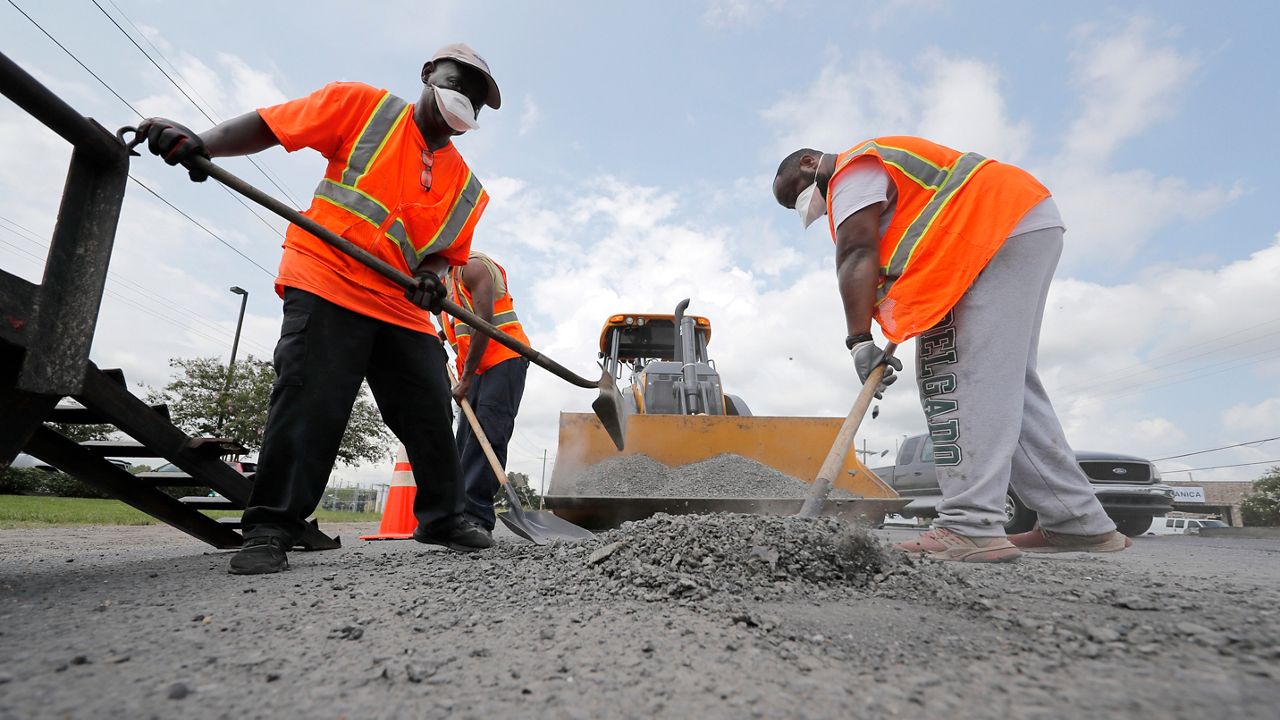 Construction workers from the Louisiana Department of Transportation and Development work in the heat on a road grading project on Airline Highway in St. Rose, La., Tuesday, Aug. 13, 2019. (AP Photo/Gerald Herbert)