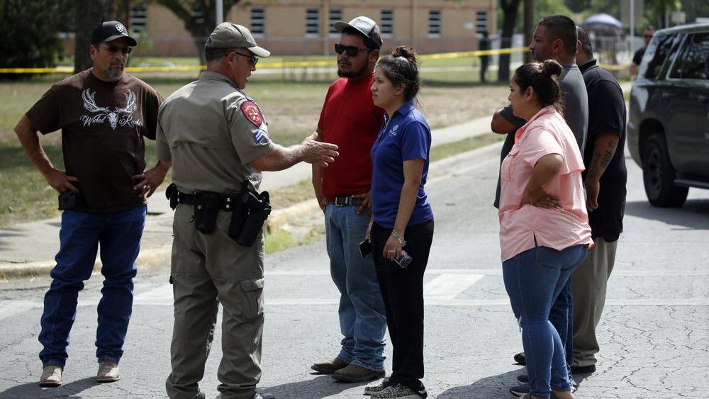 A policeman talks to people asking for information outside of the Robb Elementary School in Uvalde, Texas, Tuesday, May 24, 2022. An 18-year-old gunman opened fire at the Texas elementary school, killing multiple people. Gov. Greg Abbott says the gunman entered the school with a handgun and possibly a rifle. AP Photo/Dario Lopez-Mills)