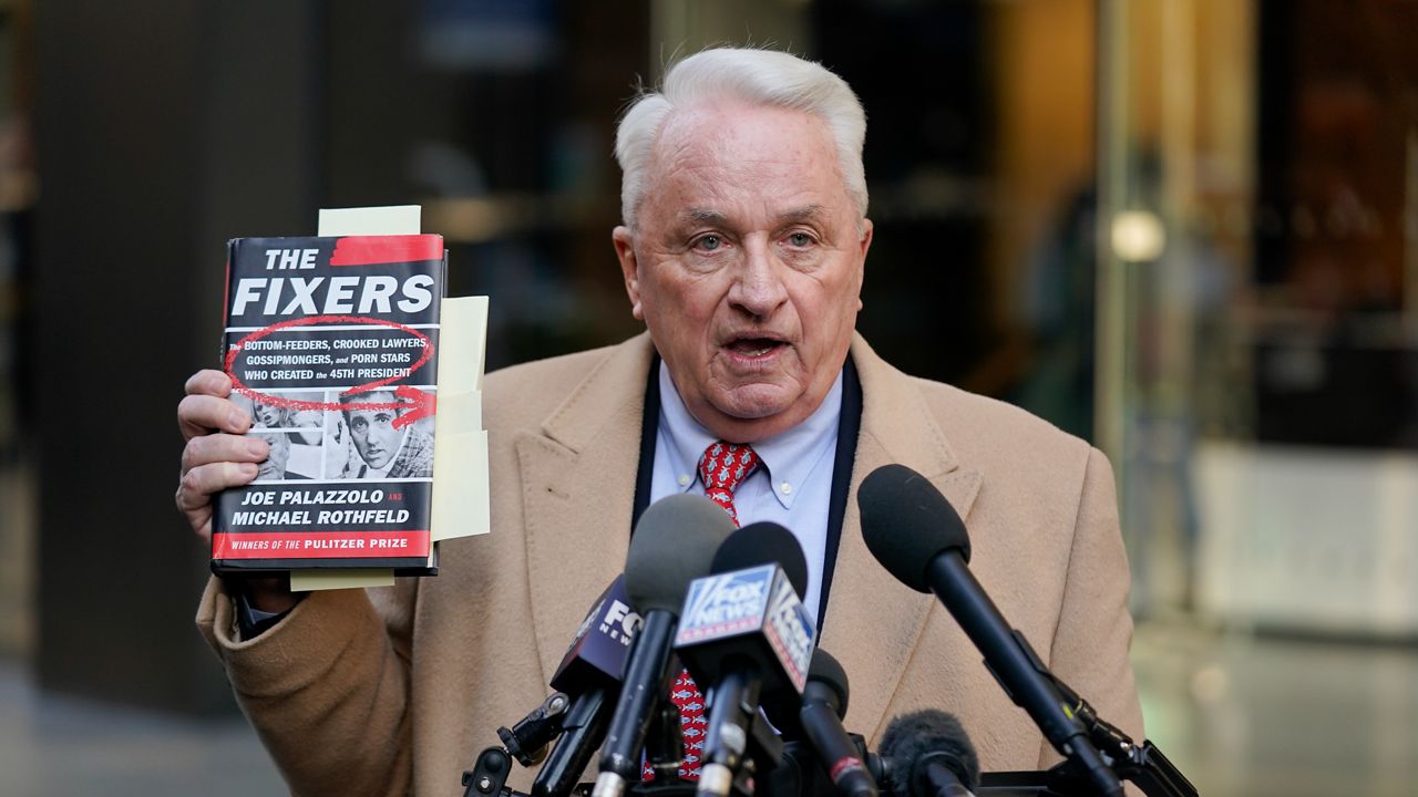 Attorney Bob Costello holds up a book while talking to reporters after testifying before a grand jury investigating Donald Trump in New York, Monday, March 20, 2023. (AP Photo/Seth Wenig)