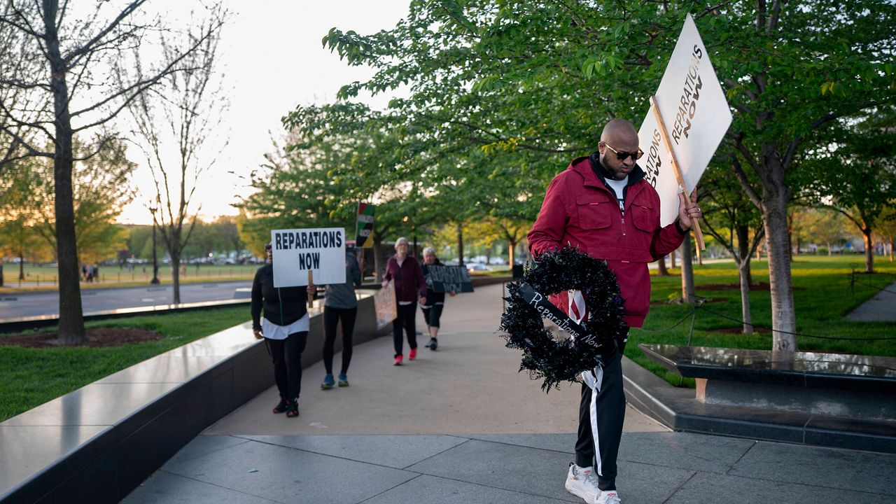The Rev. Robert Turner walks near the National Museum of African American History and Culture as part of his monthly walk from Baltimore to Washington to raise awareness of reparations on Wednesday, April 16, 2025, in Washington. (AP Photo/Nathan Howard)