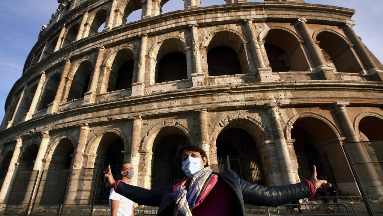 A tourist guide wearing a mask speaks in front of the ancient Colosseum in Rome on Oct. 13, 2020. (AP Photo/Andrew Medichini, File)
