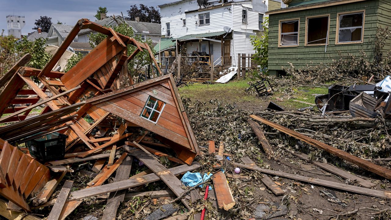 A destroyed children's playhouse rests behind the heavily damaged homes owned by landlord and owner Richard Secor, on Henry Street in South Rome, N.Y., Tuesday, July 23, 2024, following an EF2 tornado that touched down in the population center one week earlier. Residents are vowing to rebuild. But some of the damage was so severe that the path forward is uncertain for many in this old manufacturing city, where people are more accustomed to digging out from snowstorms than from piles of rubble. (AP Photo/Craig Ruttle)