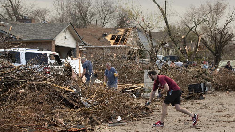 Jarrod Schneider, who lives on Oxford Drive in Round Rock, Texas, helps his neighbors clean up after a tornado heavily damaged several homes on the street on Monday ,March 21, 2022. (Jay Janner/Austin American-Statesman via AP)