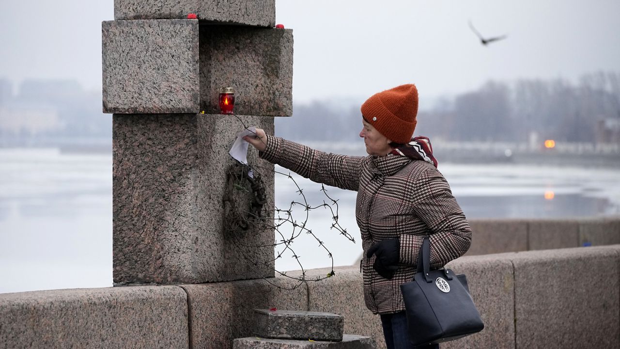 A woman places a piece of paper with words of grief for Alexei Navalny paying the last respect to him at the Memorial to Victims of Political Repression in St. Petersburg, Russia, Saturday, Feb. 24, 2024. (AP Photo/Dmitri Lovetsky)