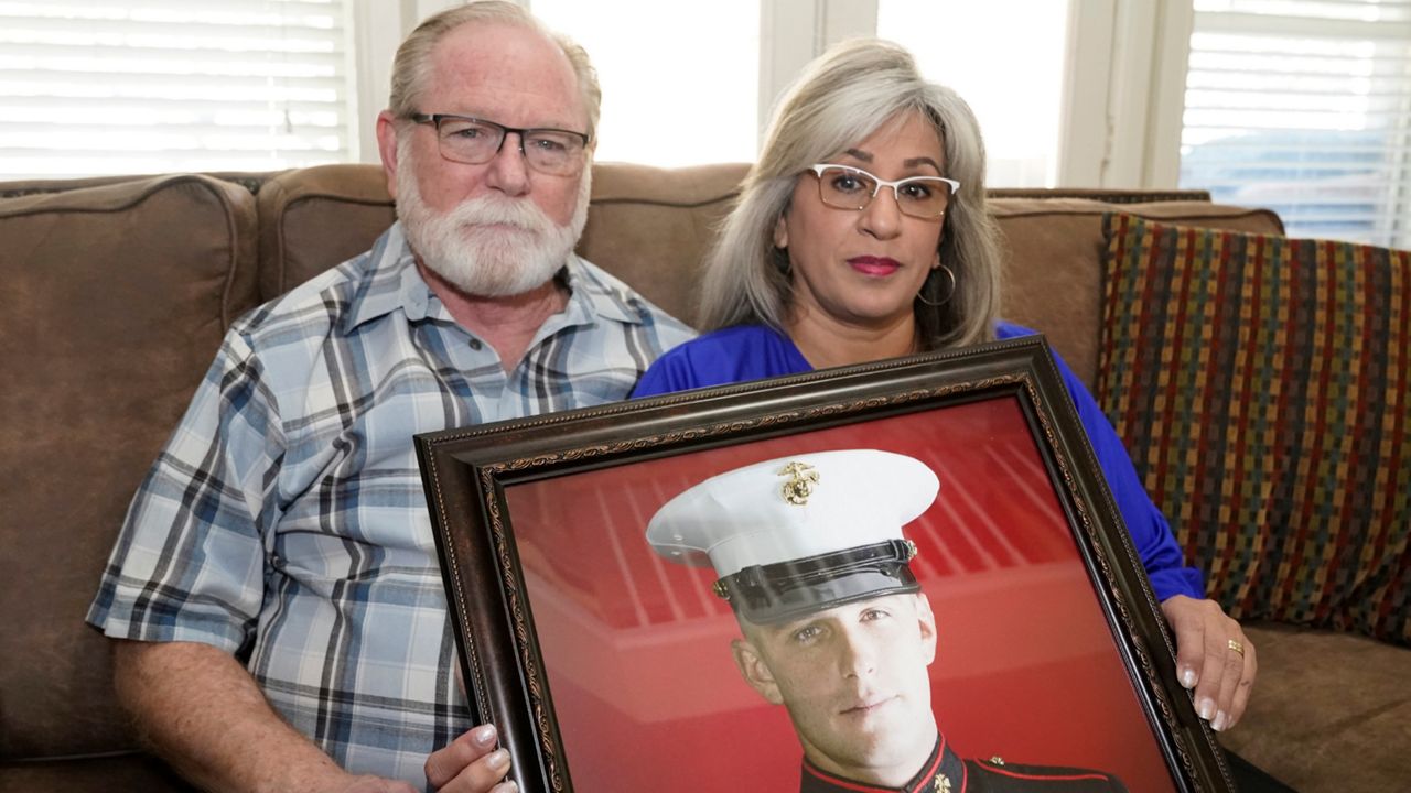 Joey and Paula Reed pose for a photo with a portrait of their son Marine veteran and Russian prisoner Trevor Reed at their home in Fort Worth, Texas, Feb. 15, 2022. (AP Photo/LM Otero, File)