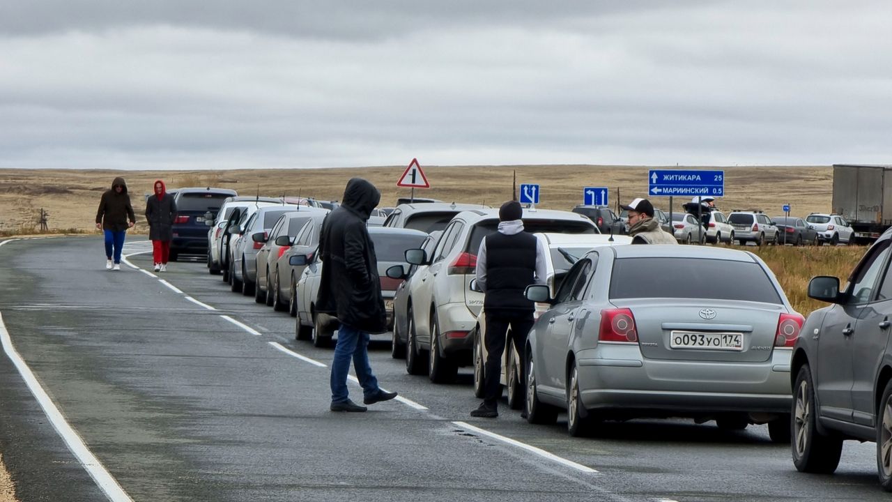 People walk next to their cars queuing to cross the border into Kazakhstan Tuesday at the Mariinsky border crossing in Russia. (AP Photo)