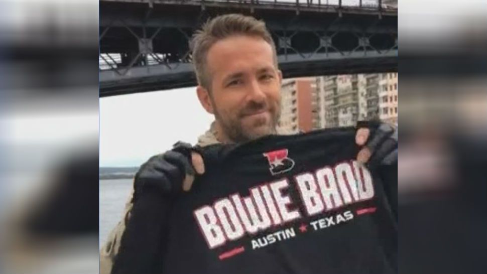 Ryan Reynolds holds up a Bowie Band T-shirt. (Courtesy: Bands of Bowie Facebook page)
