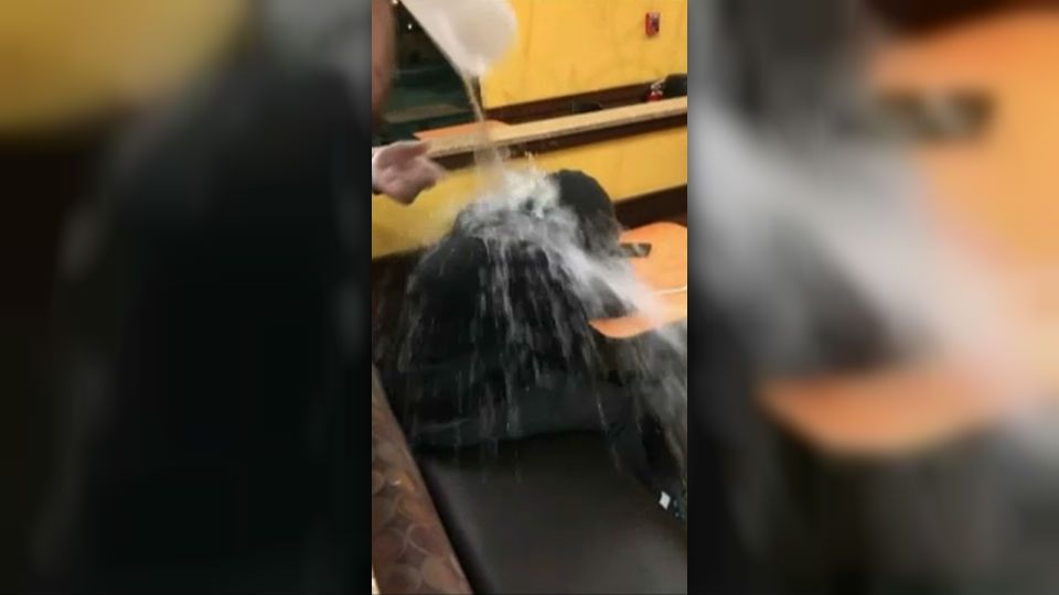 man sleeping gets water poured on him