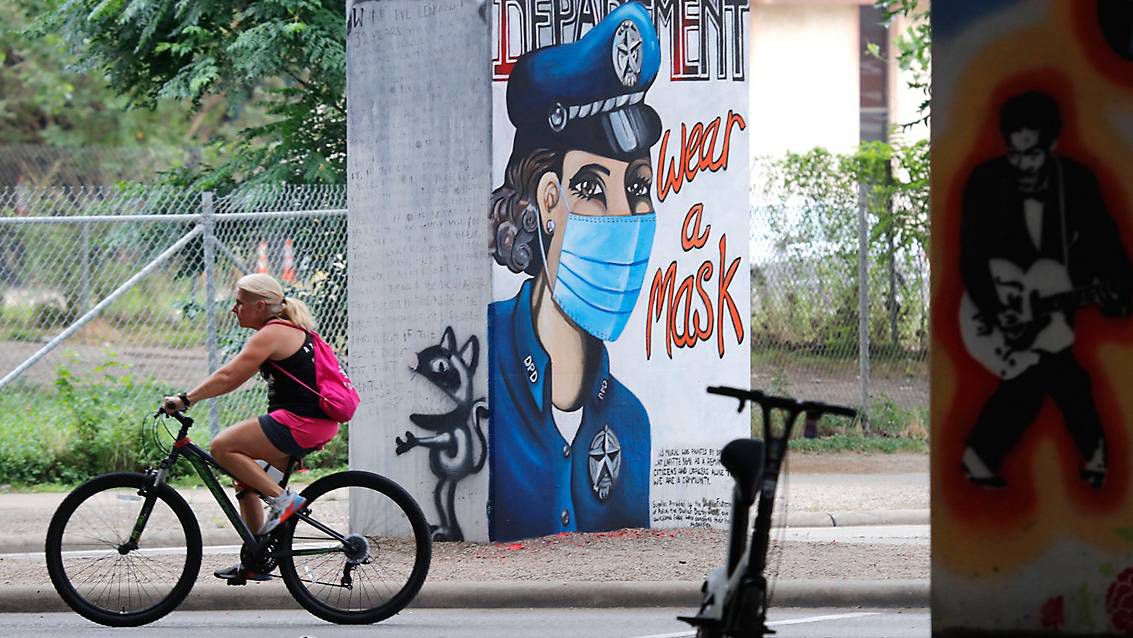 A bicyclist passes by a COVID-19 related wall painting in the Deep Ellum section of Dallas, Tuesday, June 30, 2020. (AP Photo/LM Otero)