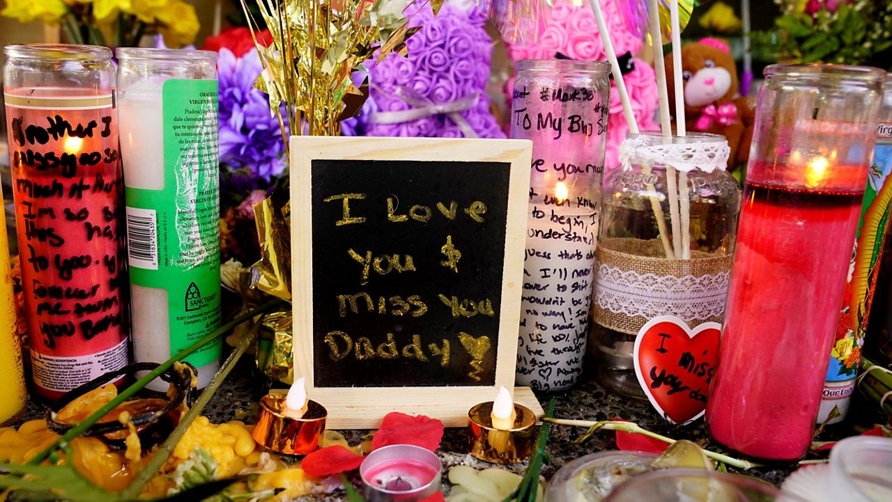A message left for one of the victims of a recent mass shooting sits among flowers and candles at a memorial in Sacramento, Calif., Saturday, April 9, 2022. (AP Photo/Rich Pedroncelli)