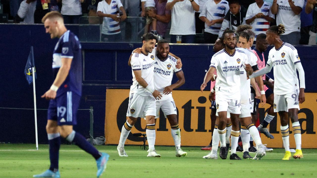 LA Galaxy midfielder Samuel Grandsir, second from left in back, celebrates with midfielder Gastón Brugman, left, after Grandsir scored a goal against the Vancouver Whitecaps during the first half of an MLS soccer match Saturday, Aug. 13, 2022, in Carson, Calif. (AP Photo/Raul Romero Jr.)