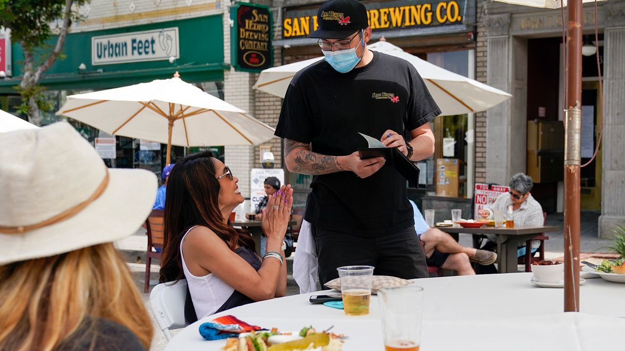 Dana Brown reacts as she orders food from Daryn Feenstra outside of San Pedro Brewing Company, Friday, May 29, 2020, in the San Pedro area of Los Angeles. Restaurants were allowed to open their dining rooms with restrictions Friday. (AP Photo/Ashley Landis)