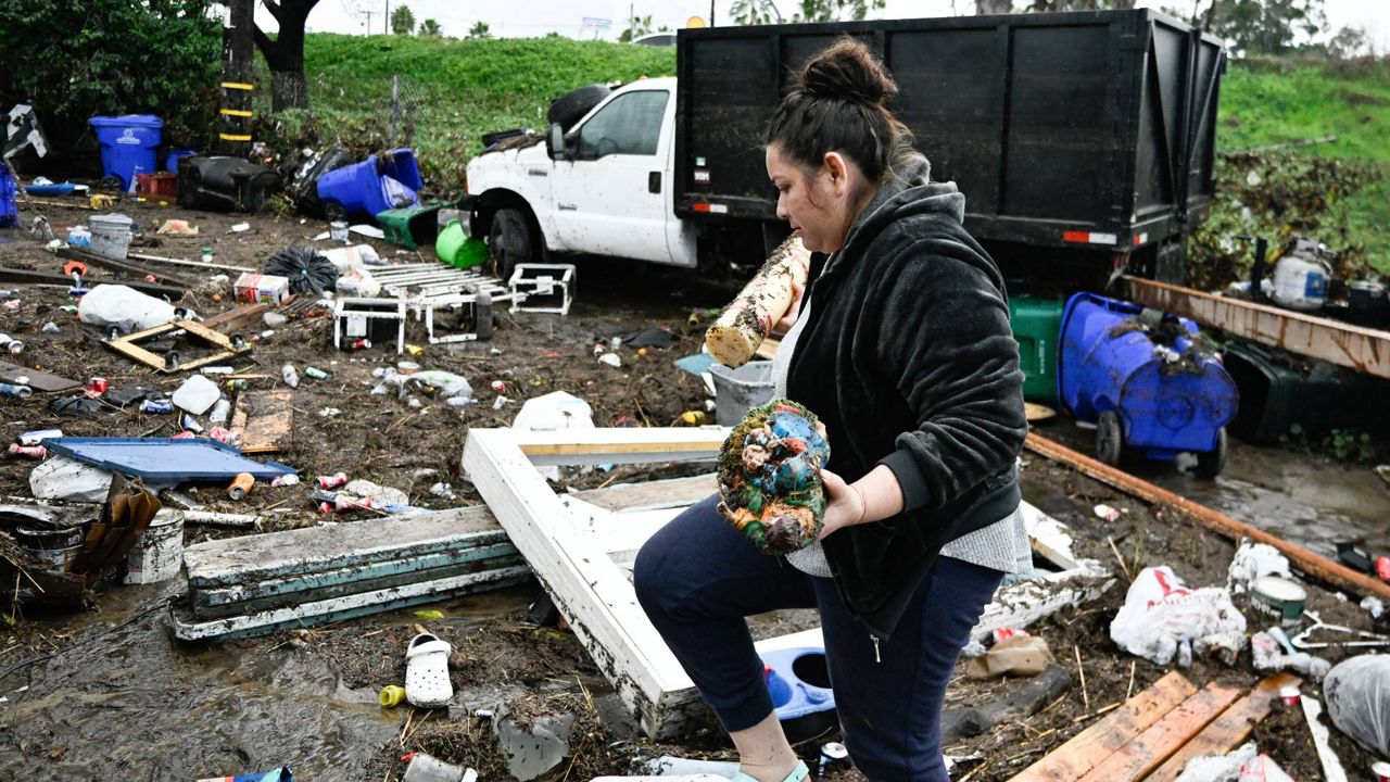 Marlene Sanchez-Barriento salvages items behind her home damaged by flooding Tuesday in San Diego. (AP Photo/Denis Poroy)