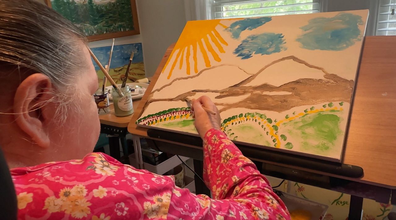 Marydith Sanders of Raleigh paints in her art room. (Spectrum News 1) 