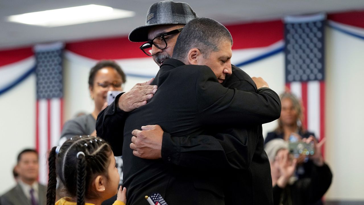 Deported veterans Mauricio Hernandez Mata, center right, and Leonel Contreras embrace after being sworn in as U.S. citizens at a special naturalization ceremony Wednesday, Feb. 8, 2023, in San Diego.  (AP Photo/Gregory Bull)