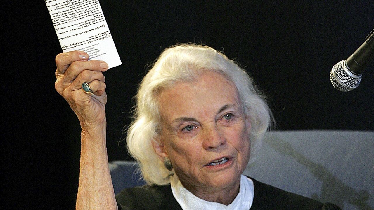 U.S. Supreme Court Justice Sandra Day O'Connor hold up a copy of the U.S. Constitution that she carries with her on Saturday, Sept. 17, 2005, at an open-air Immigration and Naturalization citizenship hearing in Gilbert, Ariz. (AP Photo/Matt York, File)