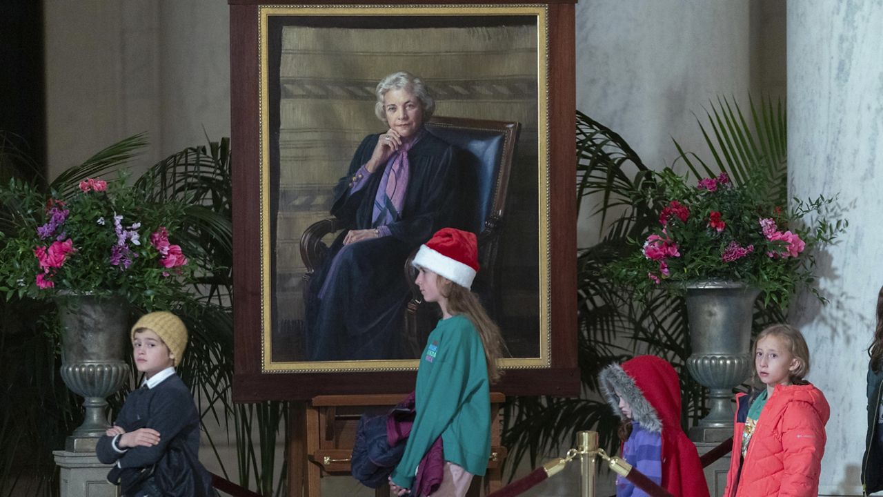 Children pass by the portait of Sandra Day O'Connor as mourners pay their respects to Supreme Court Justice Sandra Day O'Connor, whose flag-draped casket lies in the Great Hall at the Supreme Court in Washington, Monday, Dec. 18, 2023. (AP Photo/Jose Luis Magana)