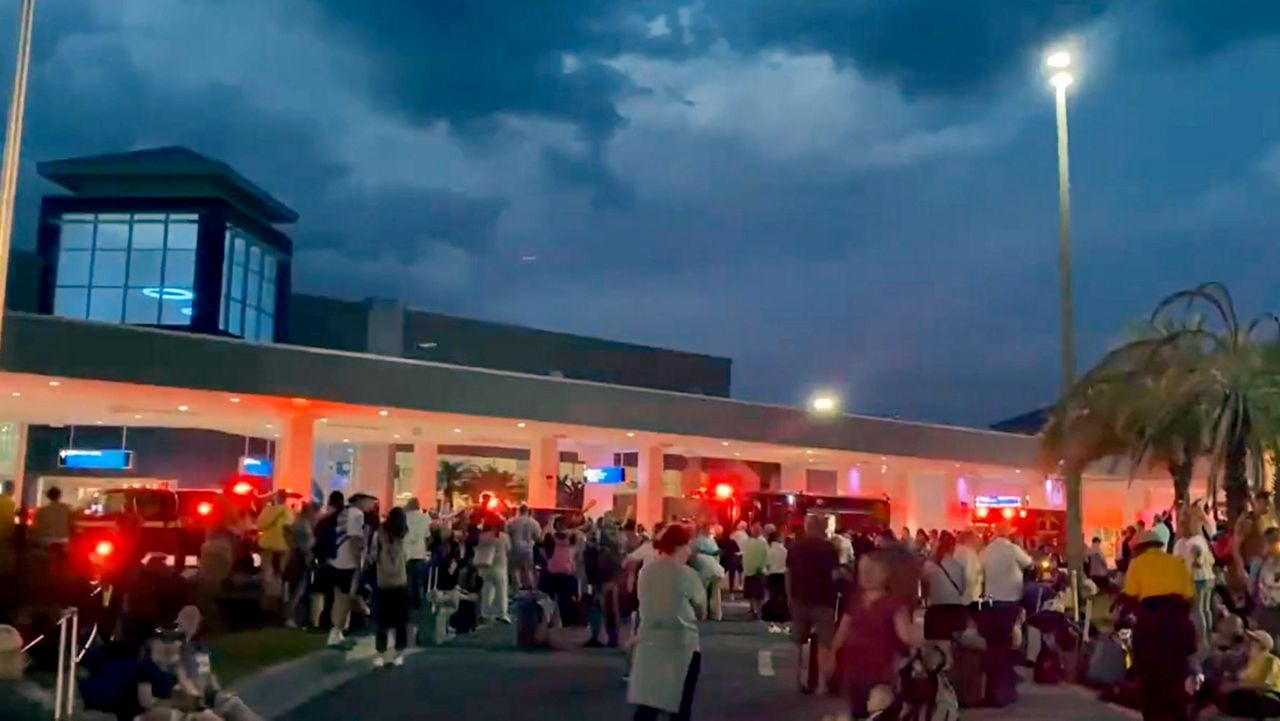 Passengers wait outside the terminal at Orlando Sanford International Airport Thursday after the report of a fire caused the building to be evacuated. (Spectrum News 13/Greg Angel)