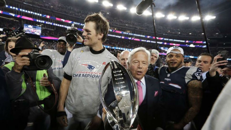New England Patriots owner Robert Kraft, center, carries the trophy between quarterback Tom Brady, left, and safety Patrick Chung as they leave the field after the AFC Championship NFL football game against the Jacksonville Jaguars, Sunday, Jan. 21, 2018. (AP Photo/David J. Phillip)