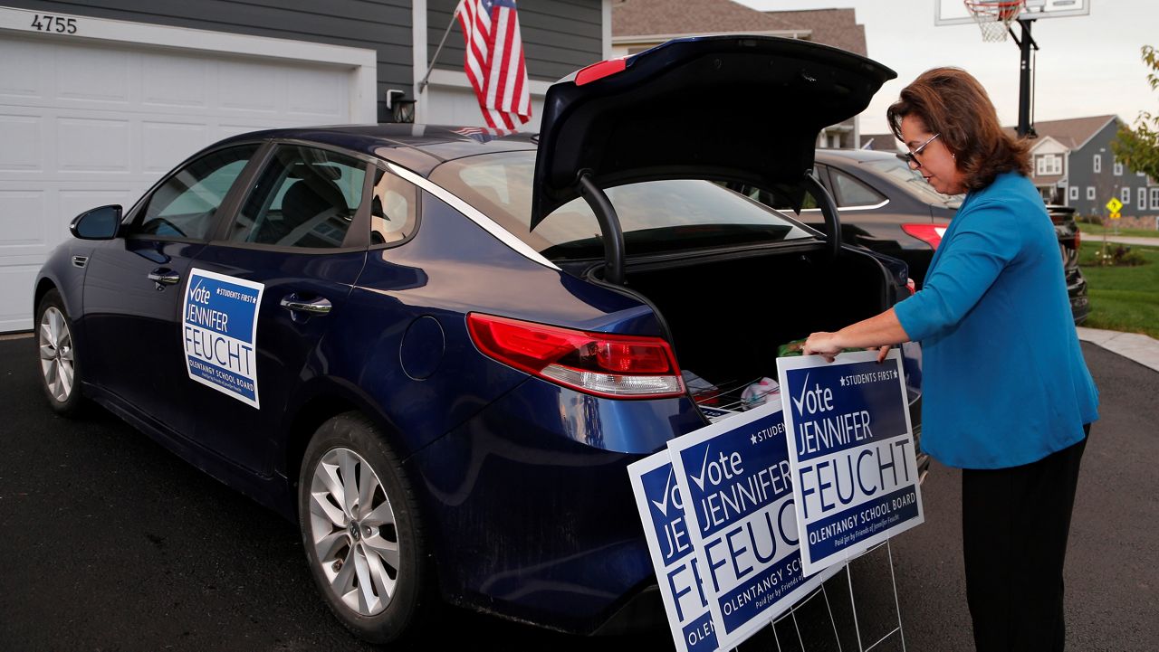 Jennifer Feucht, candidate for Olentangy Local Board of Education, delivers campaign flyers and yard signs to Brad and Tina Krider Thursday, Oct. 7, 2021, in Westerville, Ohio. (AP Photo/Jay LaPrete)  