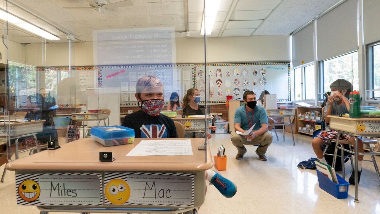 Fourth-graders sit behind plexiglass at their desks at the Osborn School in Rye, New York, on Oct. 6, 2020. (AP Photo/Mary Altaffer, File)