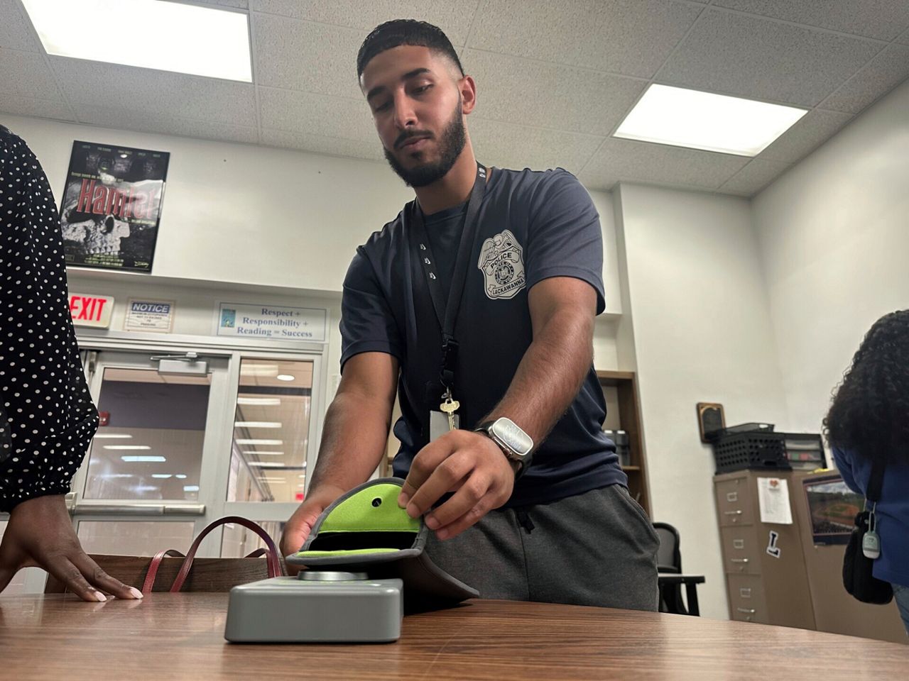 Lackawanna Police Officer Abdul Albaneh, who works with schools, demonstrates how to unlock a cellphone pouch that will prevent students from using their cellphones during the school day to improve student engagement, in Lackawanna, N.Y., Aug. 19, 2024, for when school resumes in September.