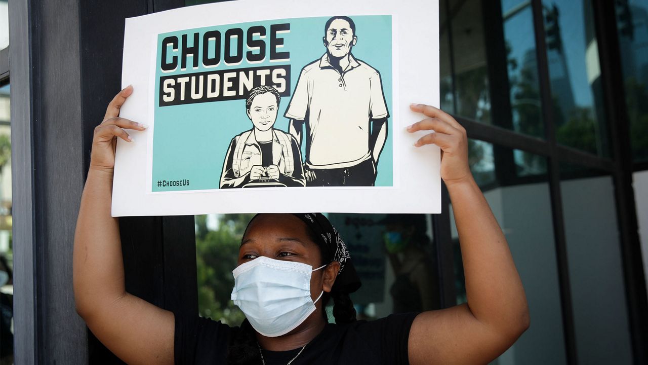 A demonstrator holds a sign Monday, Aug. 3, 2020, in Los Angeles. Parents, students, and teachers held a press conference and car caravan to call for a safe, fully funded, and racially just approach to reopening of Los Angeles schools. (AP Photo/Marcio Jose Sanchez)