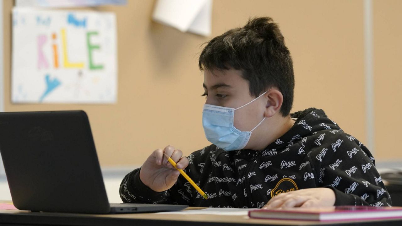 Jonny Velasquez wears a mask as he works on math in a fourth-grade classroom in Buckley, Wash. The school has had some students in classrooms for in-person learning since September of 2020. (AP Photo/Ted S. Warren)