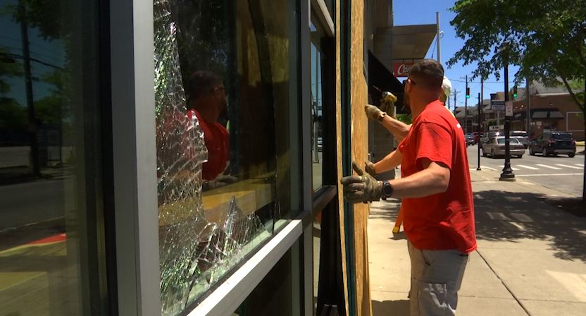 Workers help board up damaged businesses in Clifton.