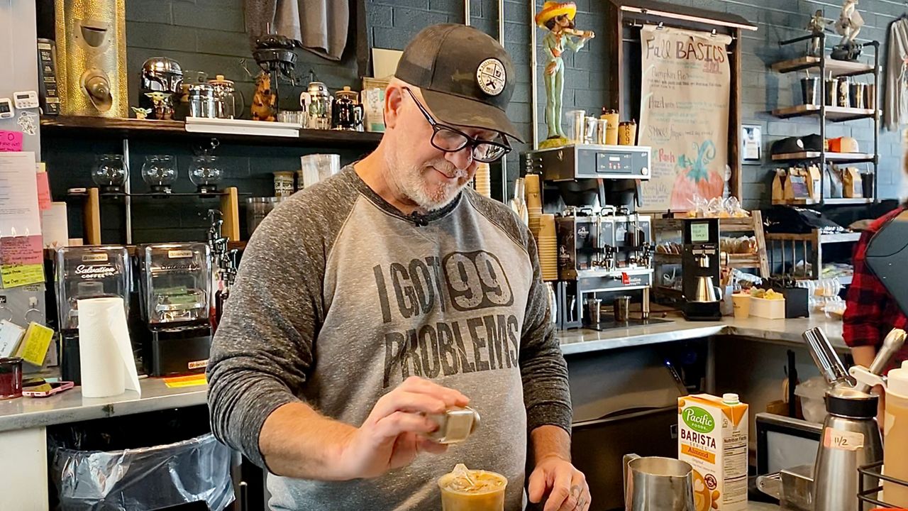 Jim Young sprinkles cinnamon on a drink.