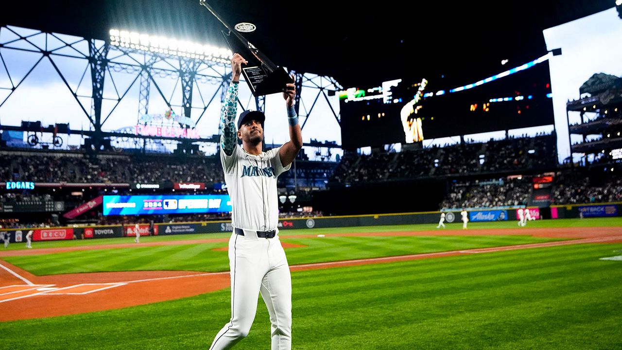 Seattle Mariners center fielder Julio Rodríguez holds up his Silver Slugger award for last season, after a presentation before the team's opening-day baseball game against the Boston Red Sox, Thursday, March 28, 2024, in Seattle. (AP Photo/Lindsey Wasson)