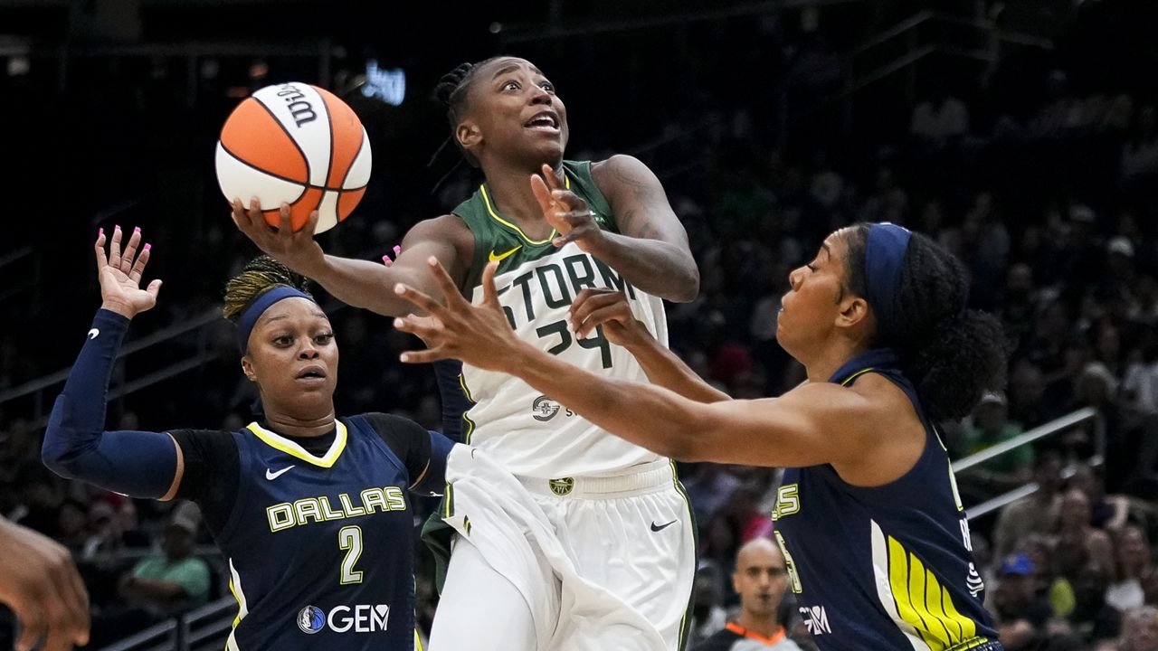 Seattle Storm guard Jewell Loyd (24) jumps up for a basket against Dallas Wings guard Odyssey Sims (2) and forward Monique Billings, right, during the first half of a WNBA basketball game, Monday, July 1, 2024, in Seattle. (AP Photo/Lindsey Wasson)