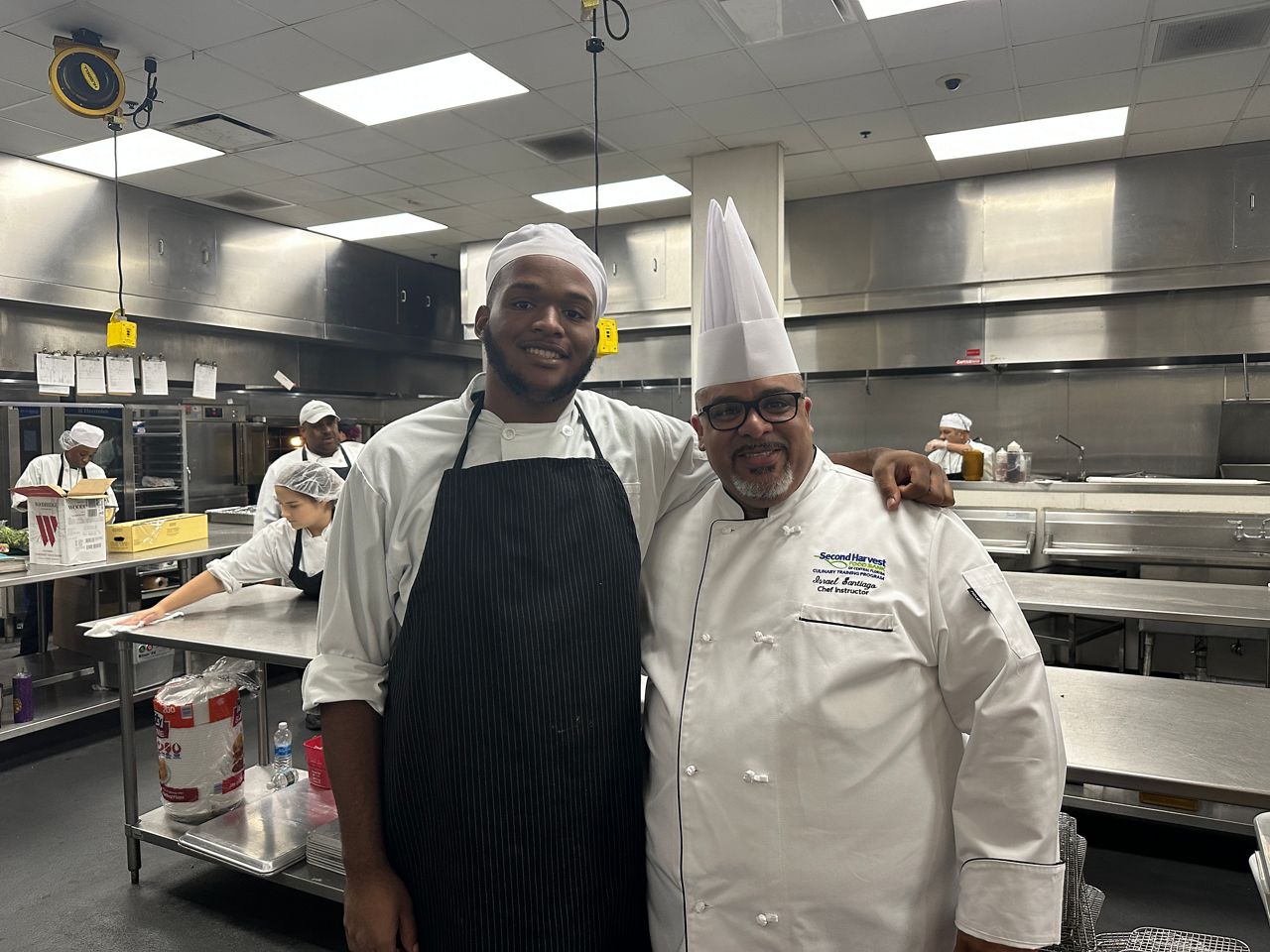 Dezmond Siracusa (left) stands with Chef Israel Santiago, who has led Second Harvest Food Bank of Central Florida's free culinary training program since it started 10 years ago. (Spectrum News/Massiel Leyva)